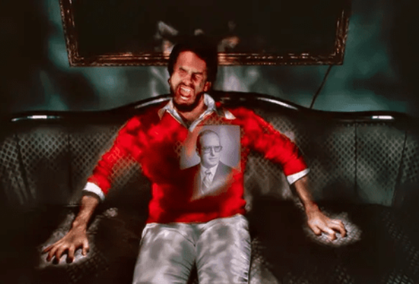 Man in red sweater sitting on sofa.