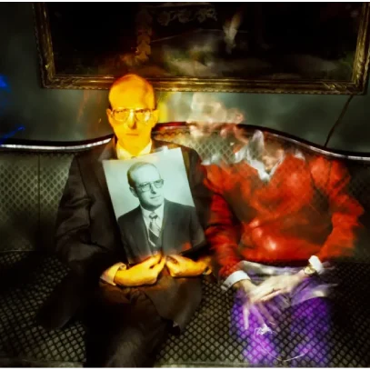 Man holding photograph, sitting on sofa.